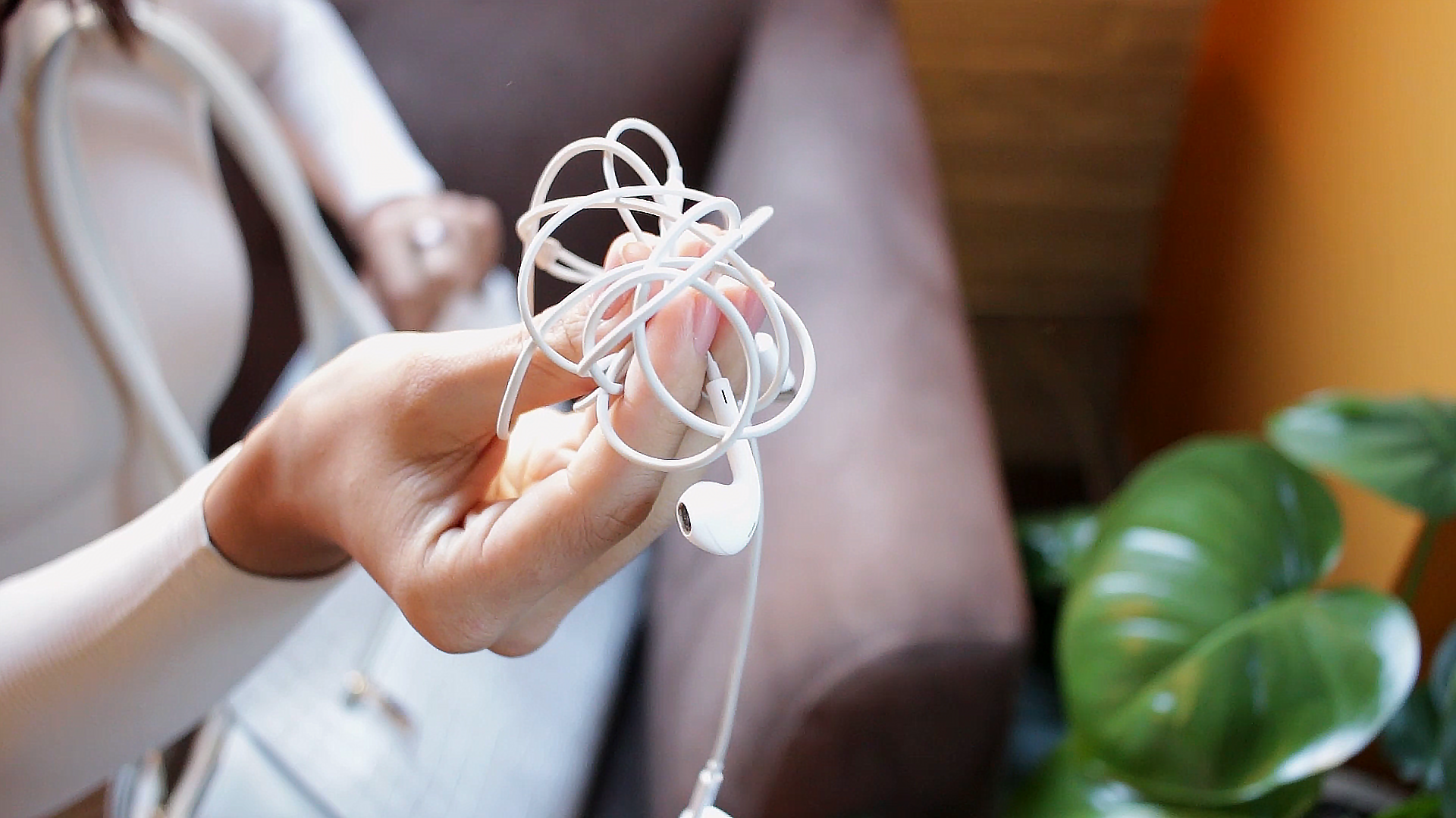 A woman holding a tangled earbuds