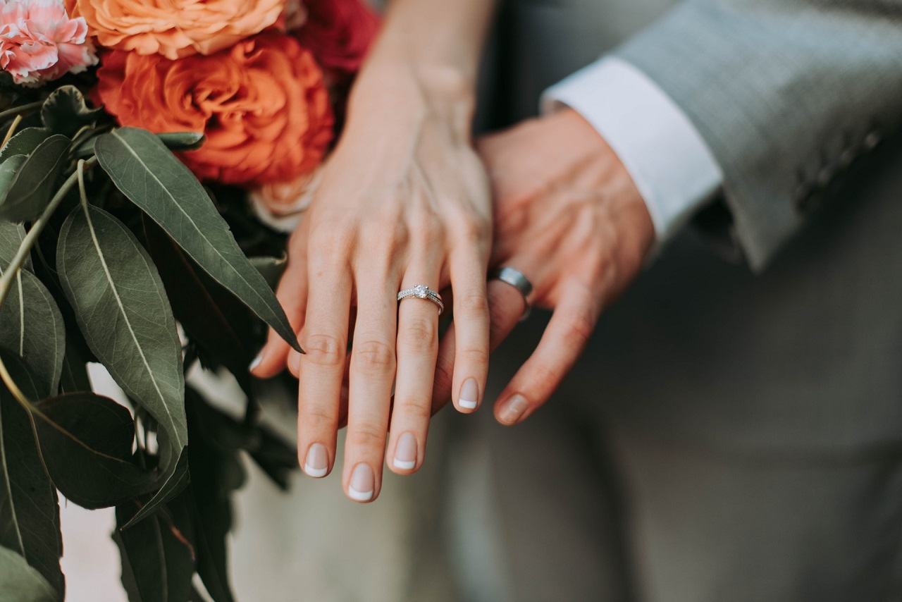 The left hands of the bride and groom, with their wedding bands