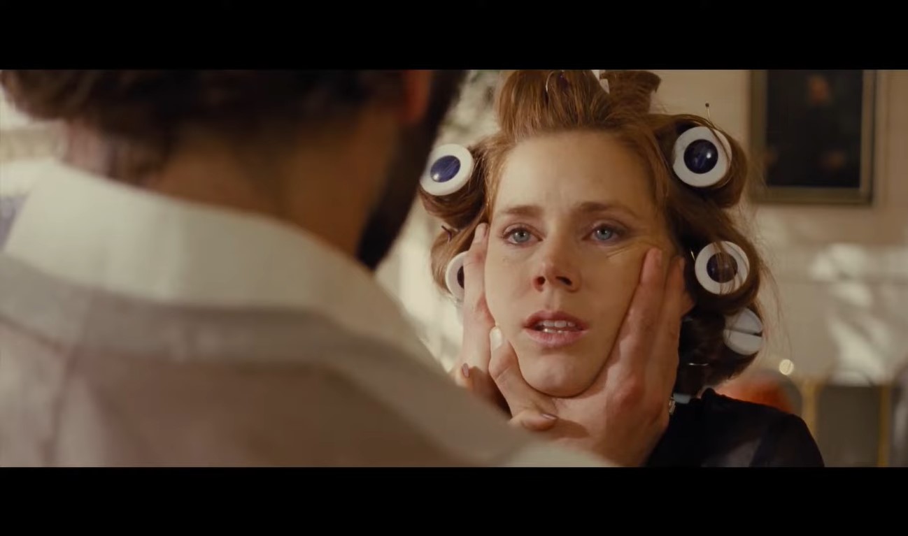 Bradley Cooper, with back against the camera, cupping the face of Amy Adams in ‘American Hustle’