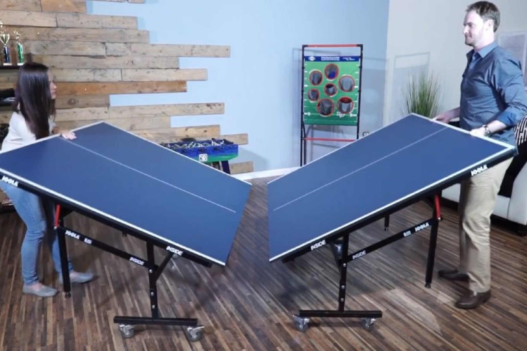 A man and a woman folding a ping pong table
