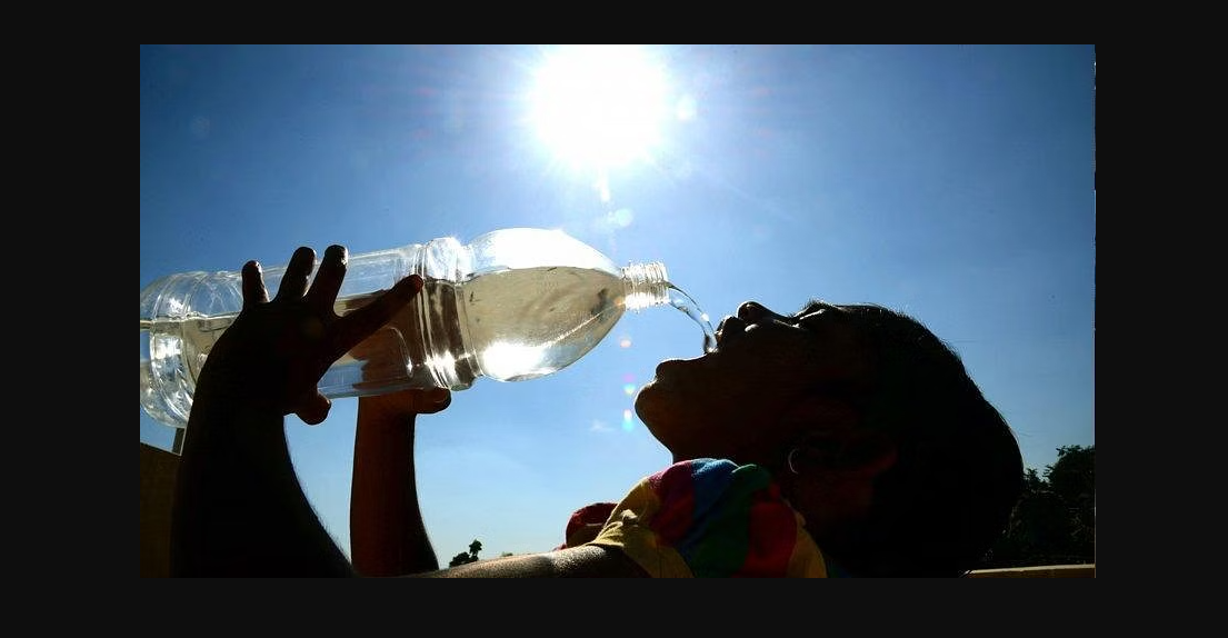 A woman drinking water from a transparent PET bottle under the shiny sun
