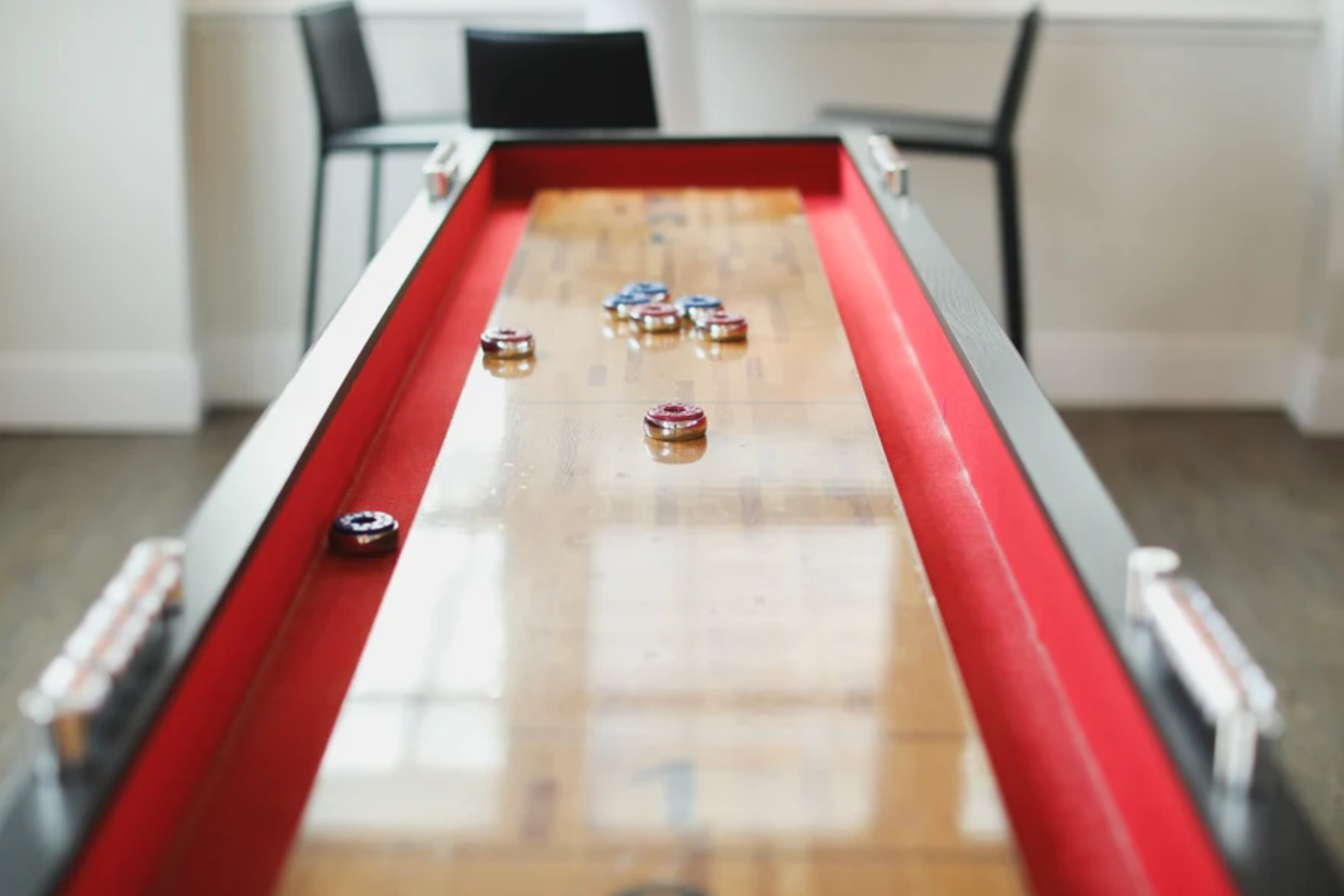 Wooden shuffleboard with eight pucks, four blue and four red