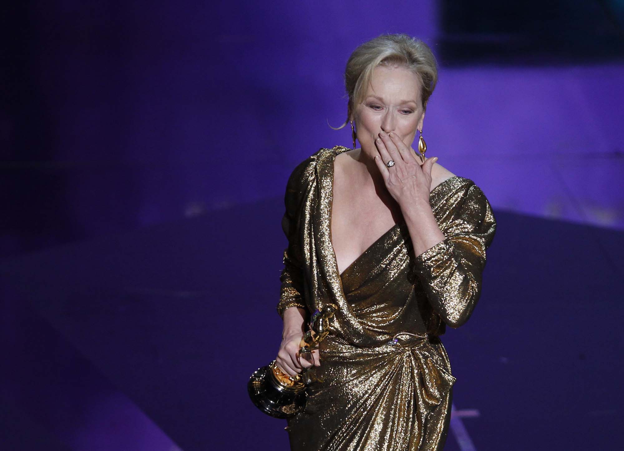 Meryl Streep wearing a gold dress with hand on her mouth
