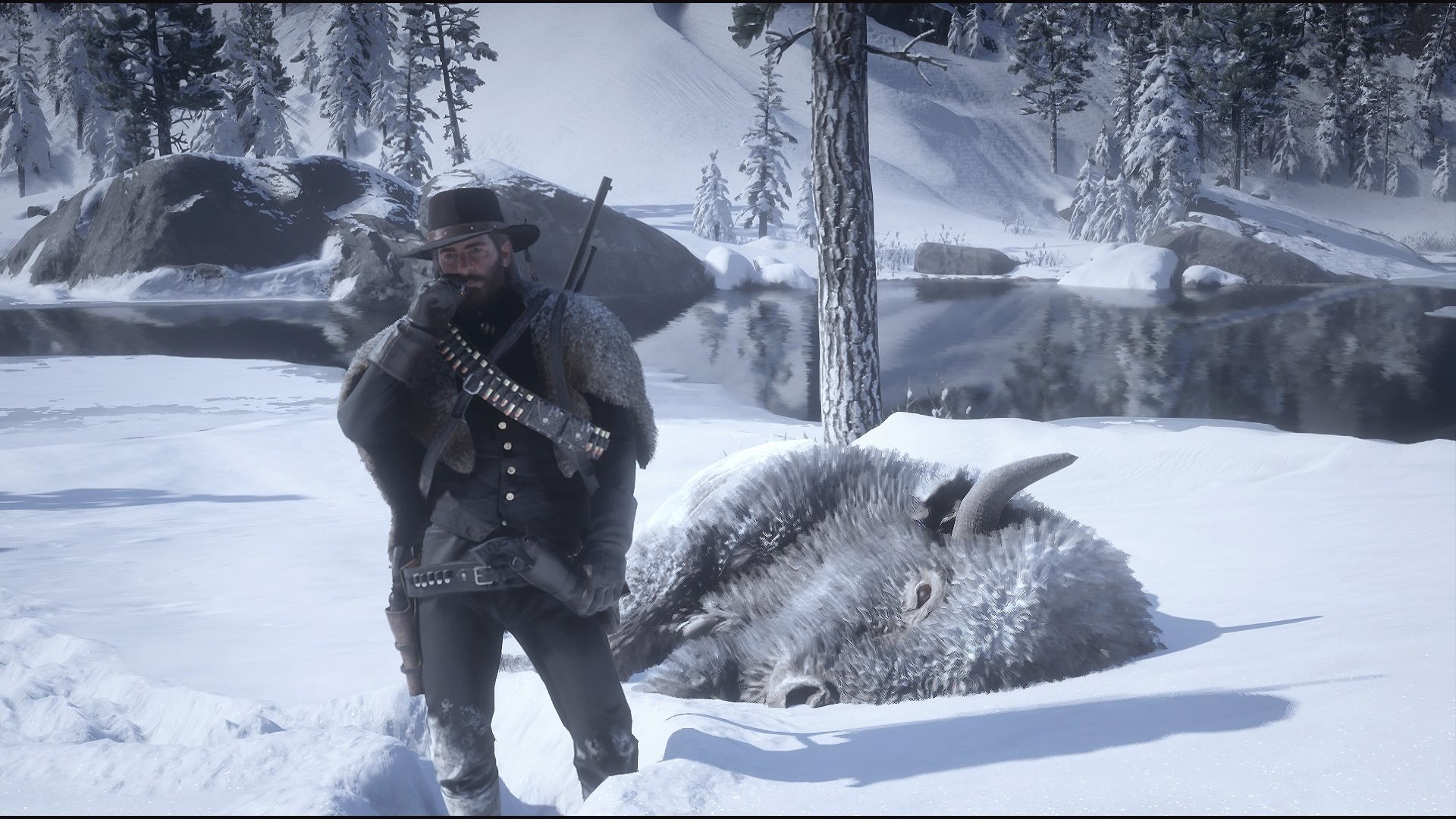 A hunter with a rifle on his back and a dead animal on the snowy ground.