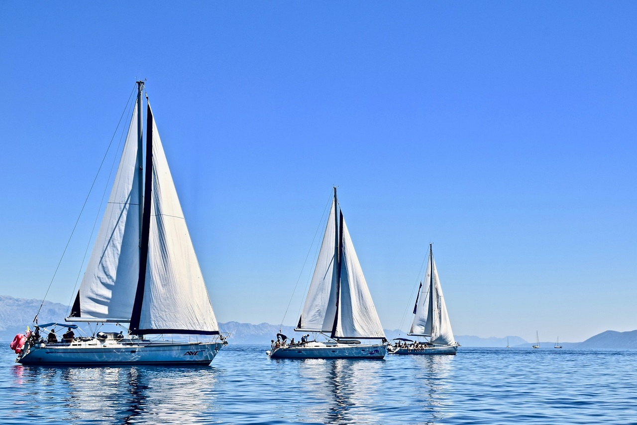 Rich people aboard three sailboats with white mast in Croatia