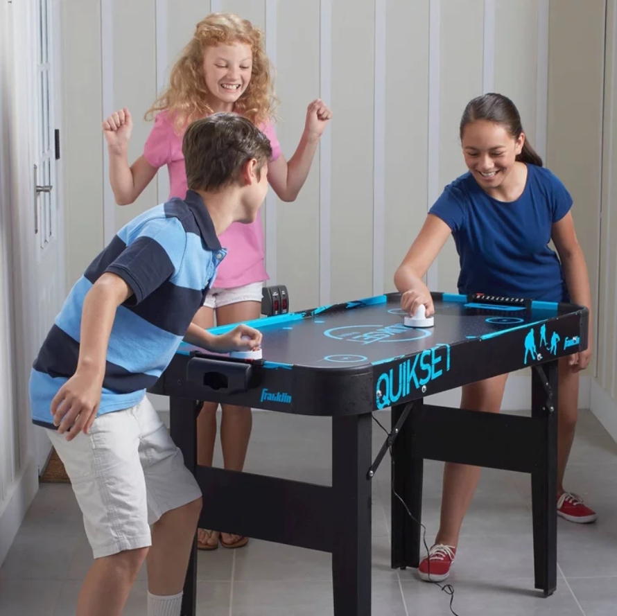 Three kids playing with Franklin Quikset Air Hockey Table