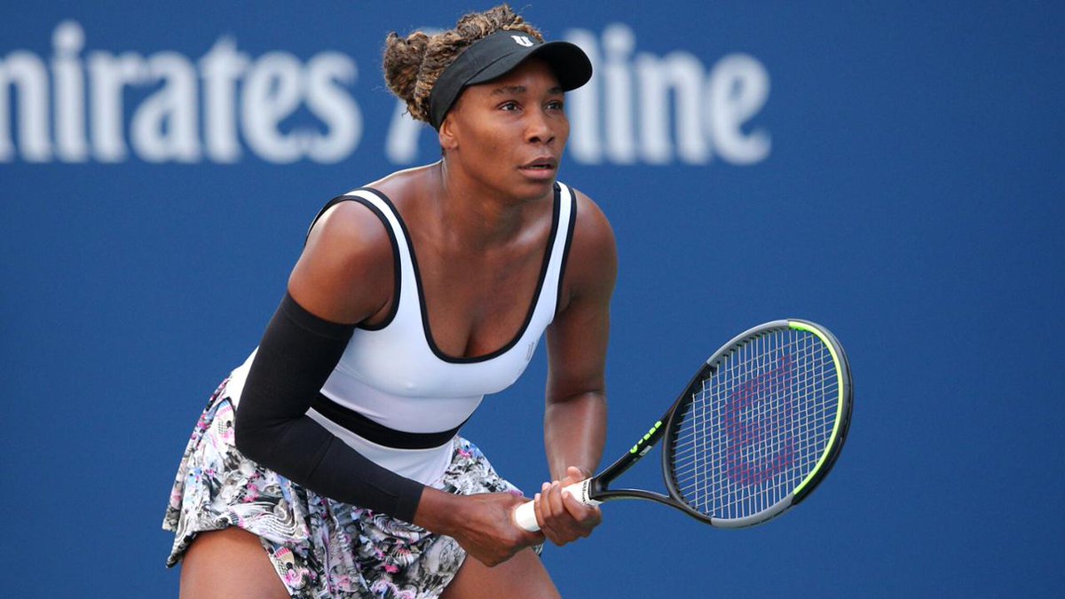 Venus Williams wearing a white sports dress while holding a tennis racket