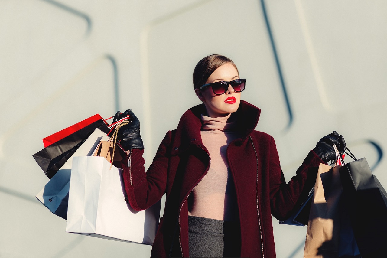 A rich woman outdoors in eyeglasses and leather gloves holding shopping bags with both hands