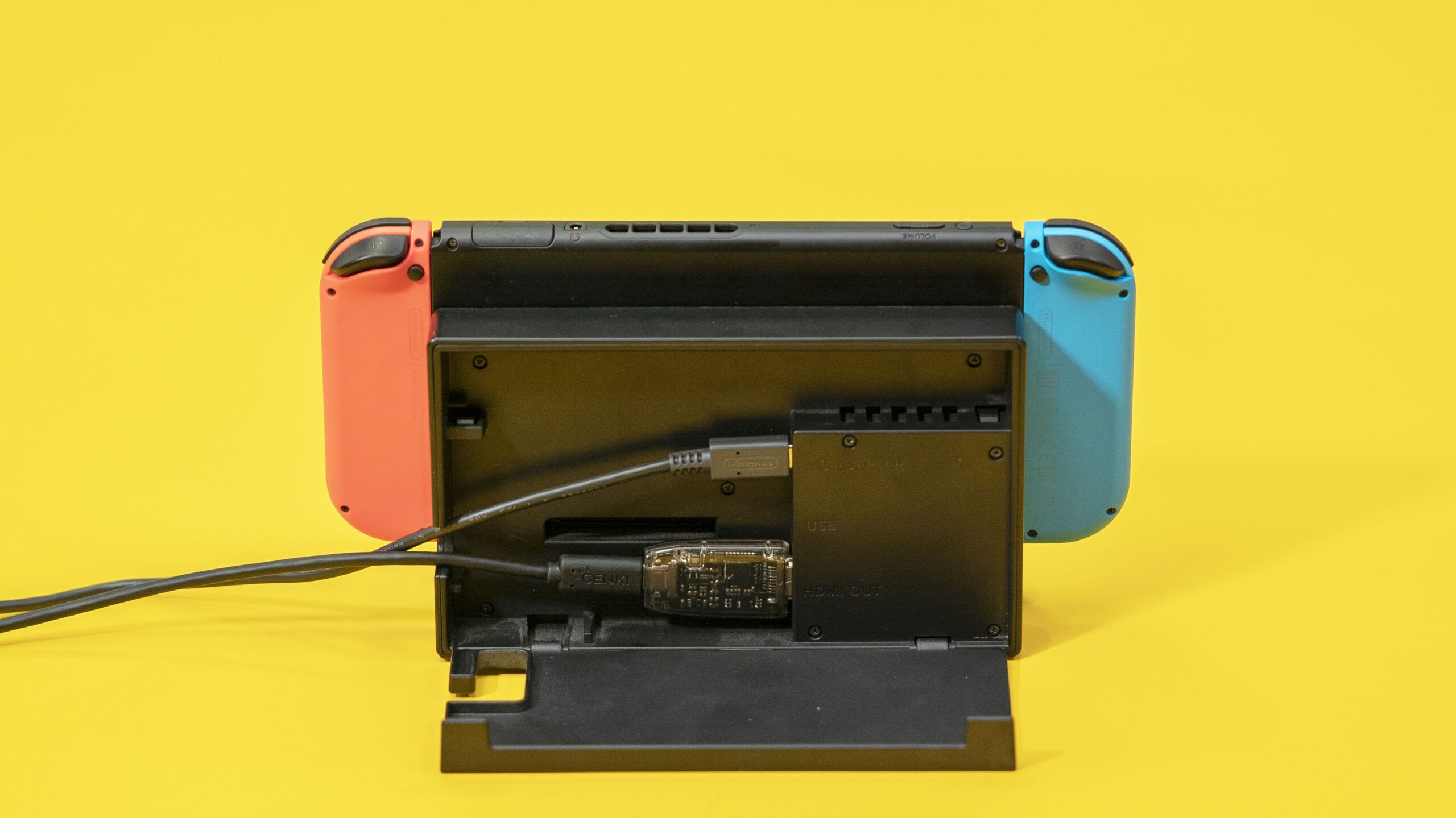 Playstation with Genki arcade device attached to it on a yellow background