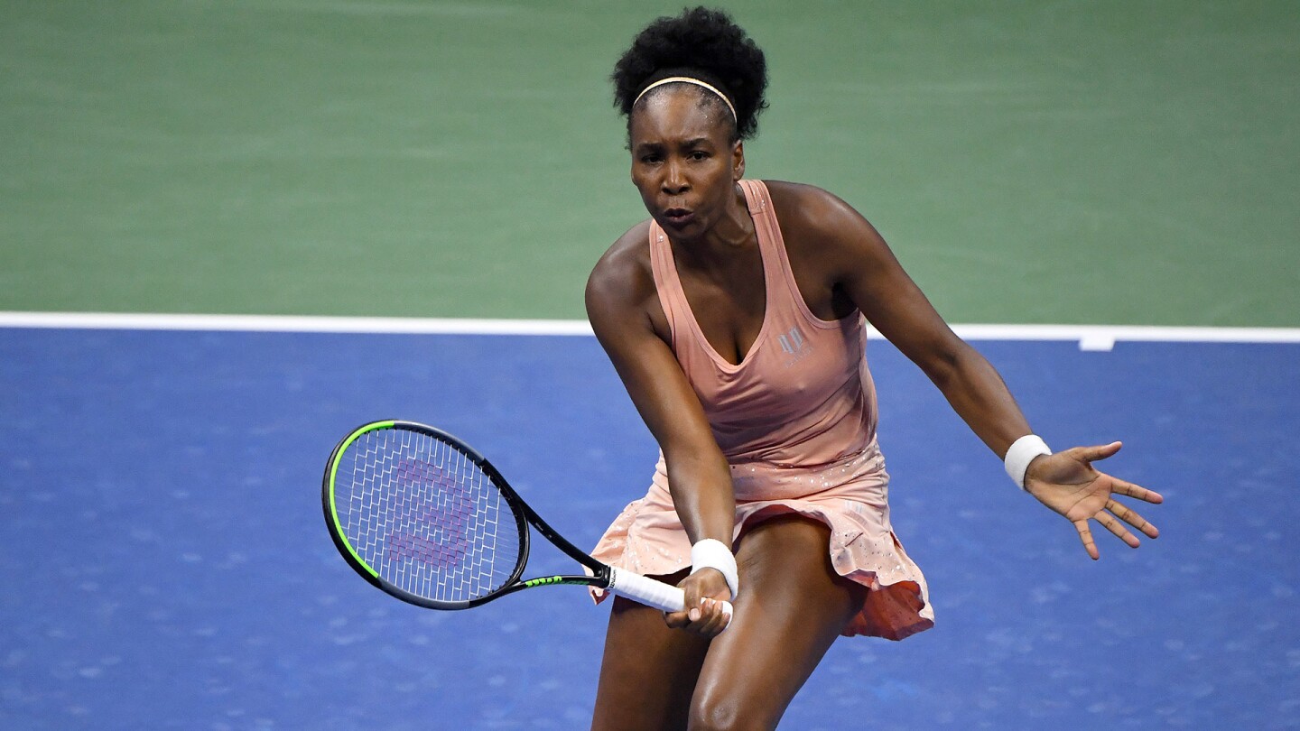 Venus Williams wearing a peach sports dress while holding a tennis racket