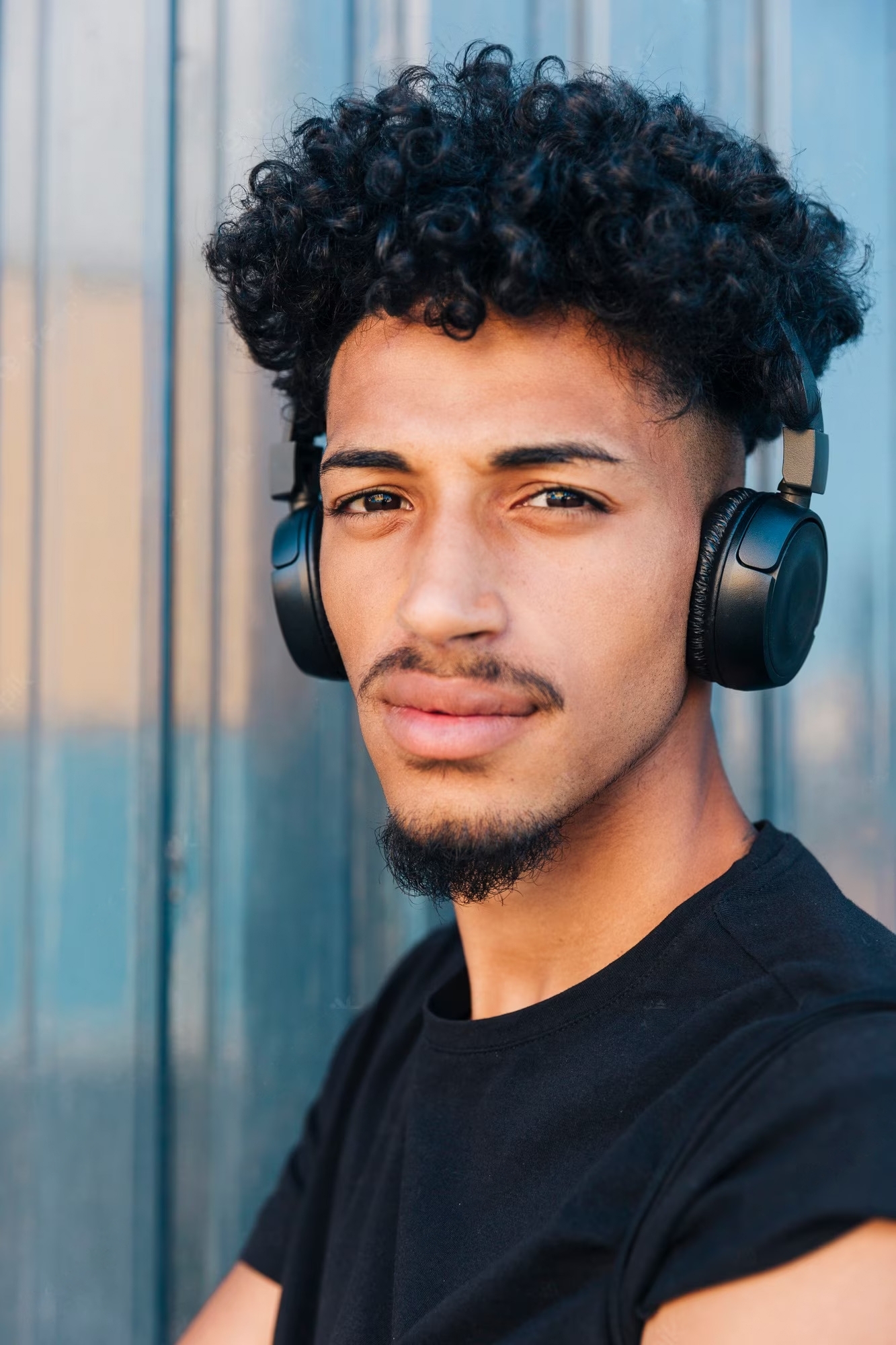 A man with curly hair wearing headphone