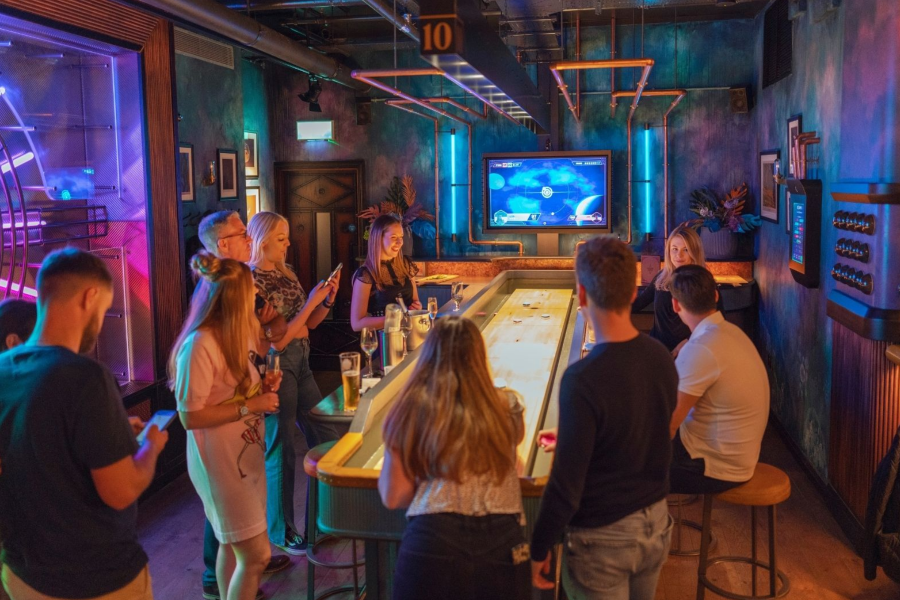 A group of young people playing shuffleboard with automated scoring