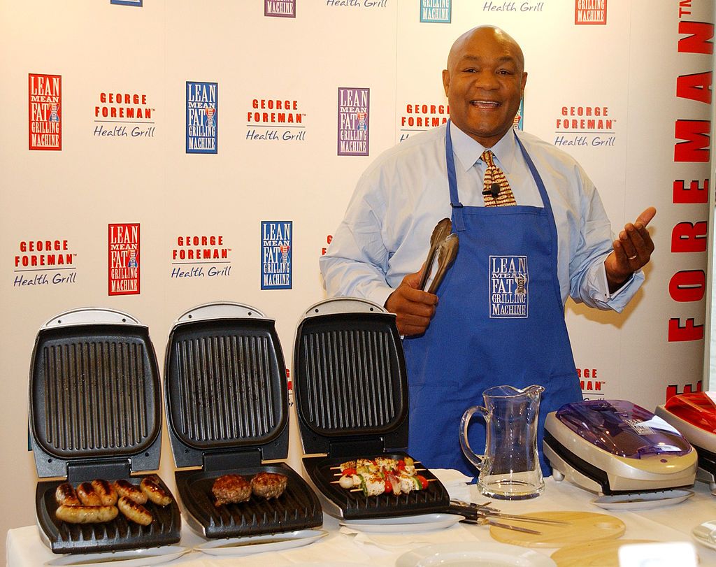 George Foreman wearing a blue apron with George Foreman Grills