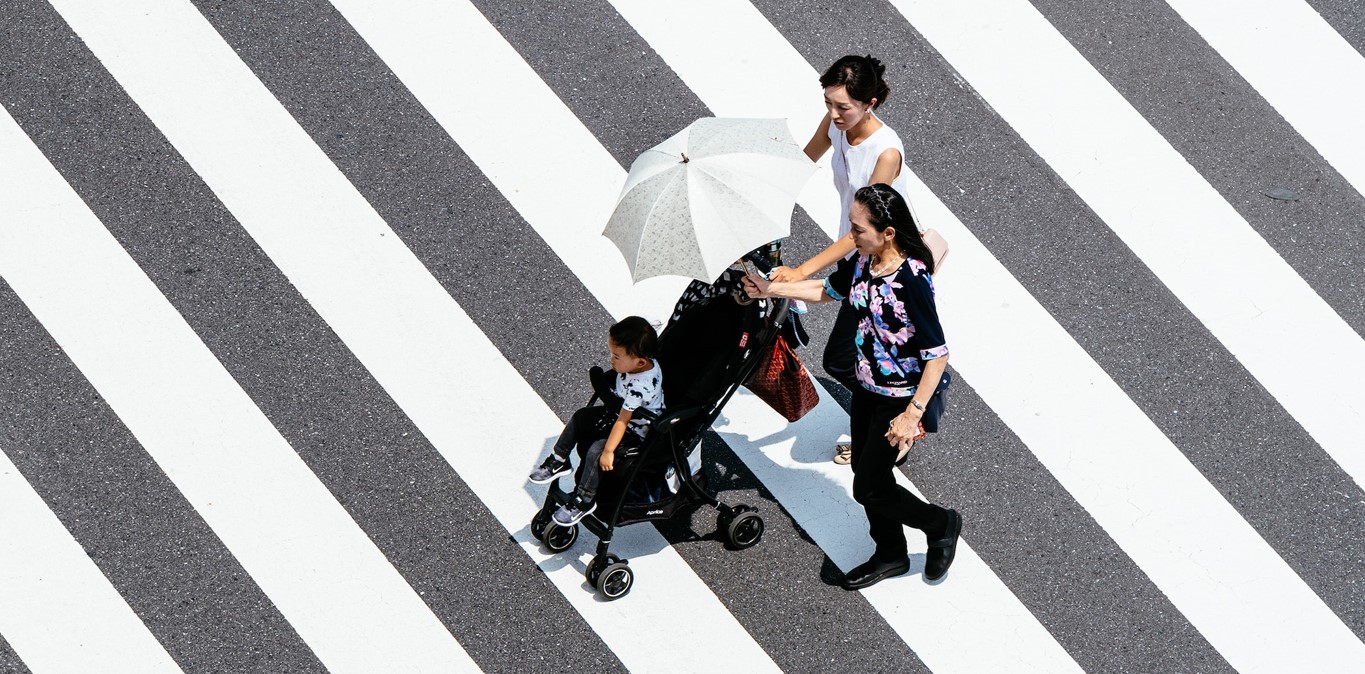 A Japanese mother pushing her baby in a stroller, with baby’s grandmother in a pedestrian crossing in Tokyo