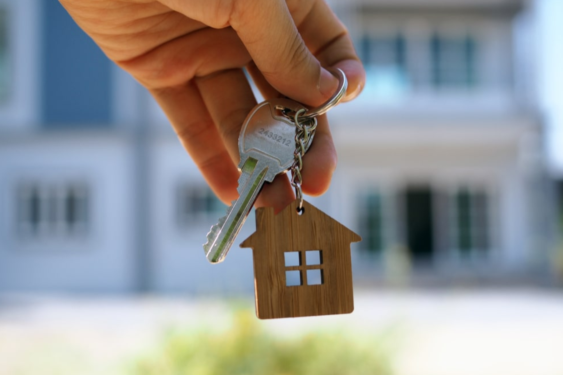 A person's hand clutching a key to the home