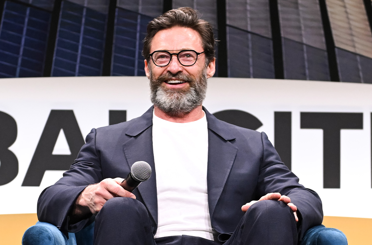 Hugh Jackman wearing a gray coat while holding a mic