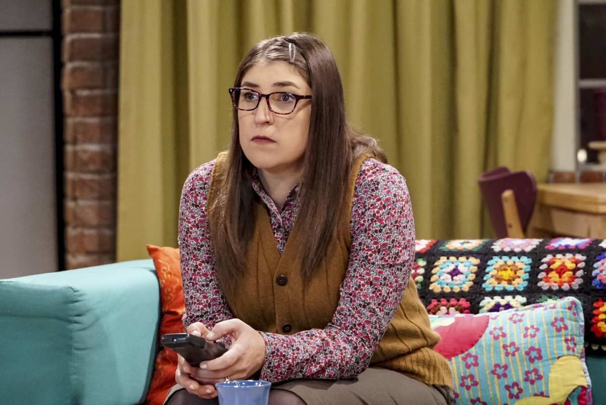 Mayim Bialik as Amy Farrah Fowler wearing a floral long sleeves and brown vest