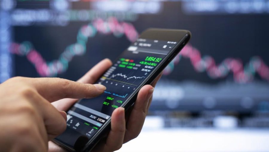 Hand holding a phone with stock chart.