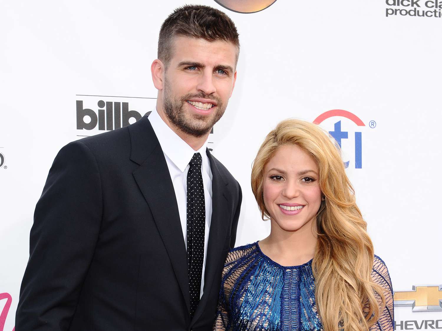 Gerard Pique wearing a black suit and Shakira wearing a blue dress