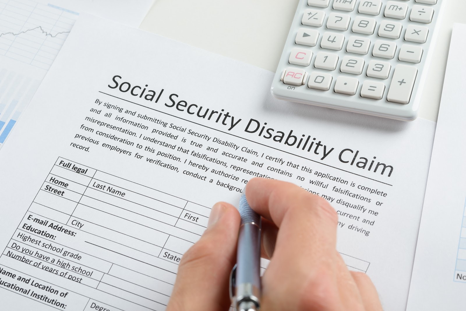 Man fill social security disability claim form and calculator on form