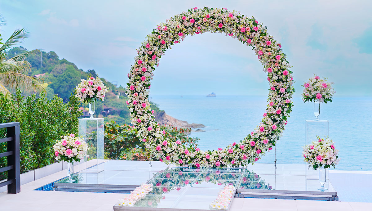 A pink floral archway on a white beach.