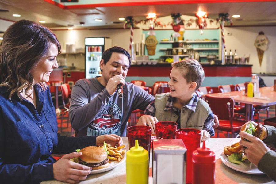 Heartwarming moment of a family enjoying a meal together, with smiles and laughter, in a classic American diner setting.