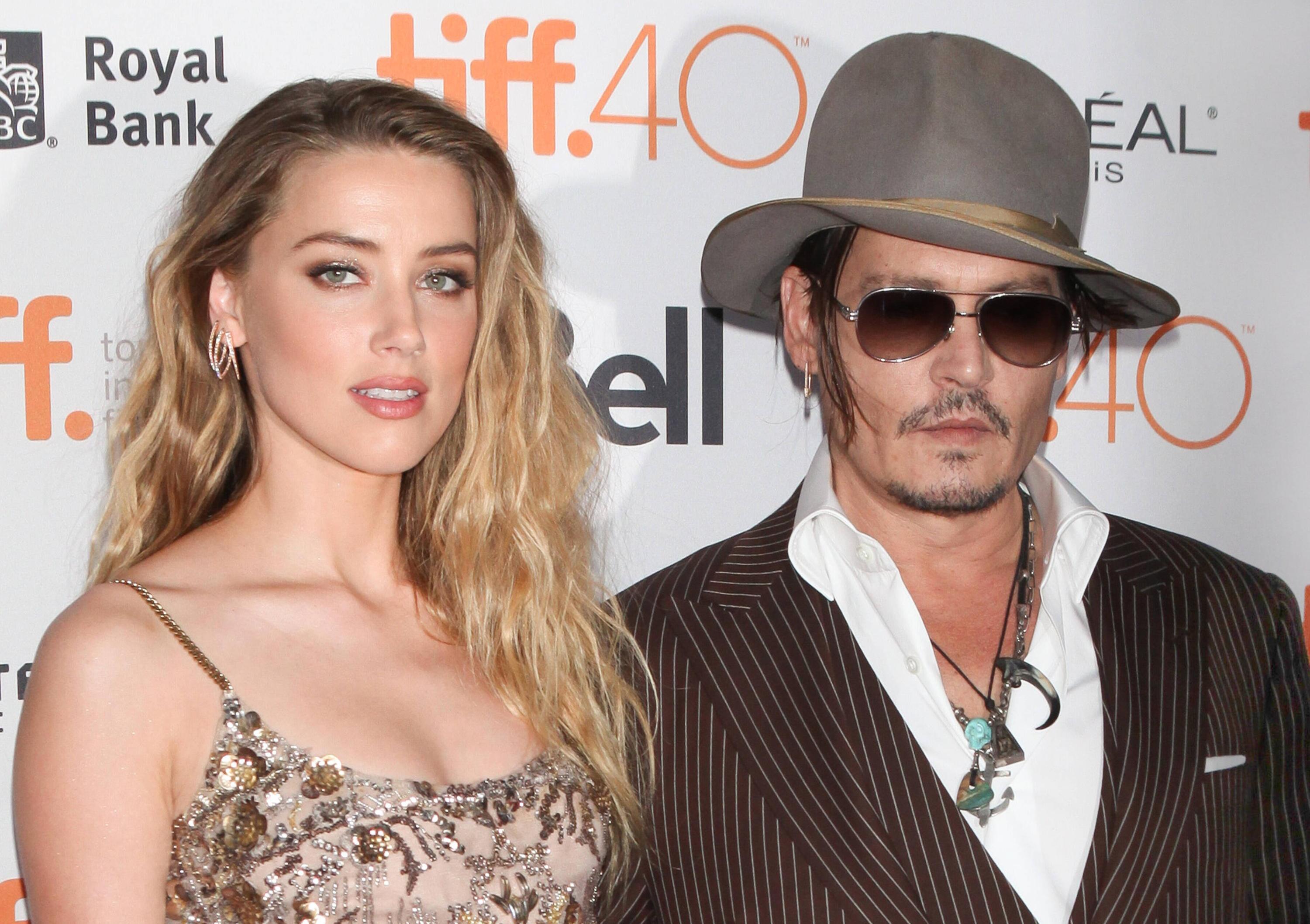 Amber Heard wearing a brown dress and Johnny Depp wearing a brown coat