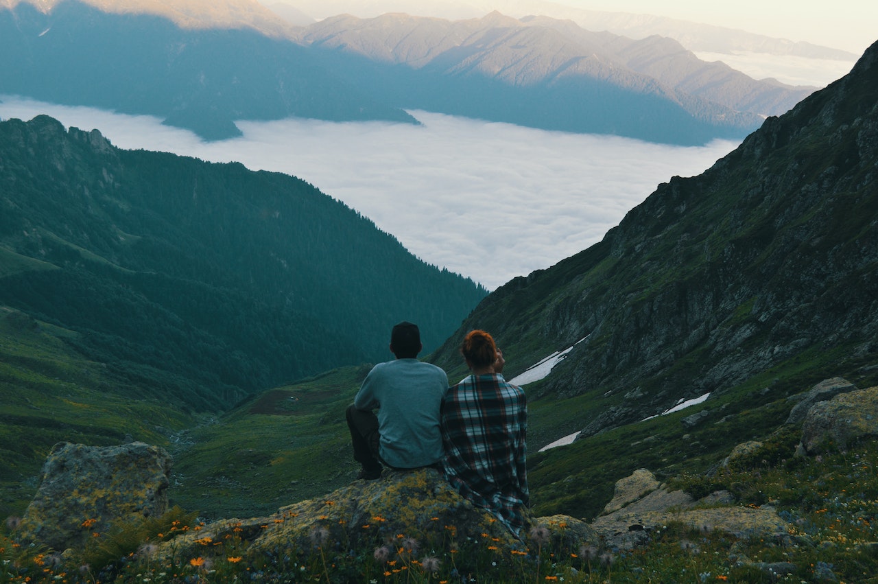 Two Person Sitting on Edge of Mountain 