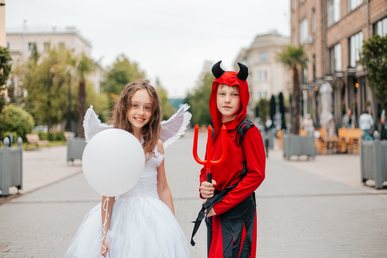Children in Angel and Devil Costumes in Street