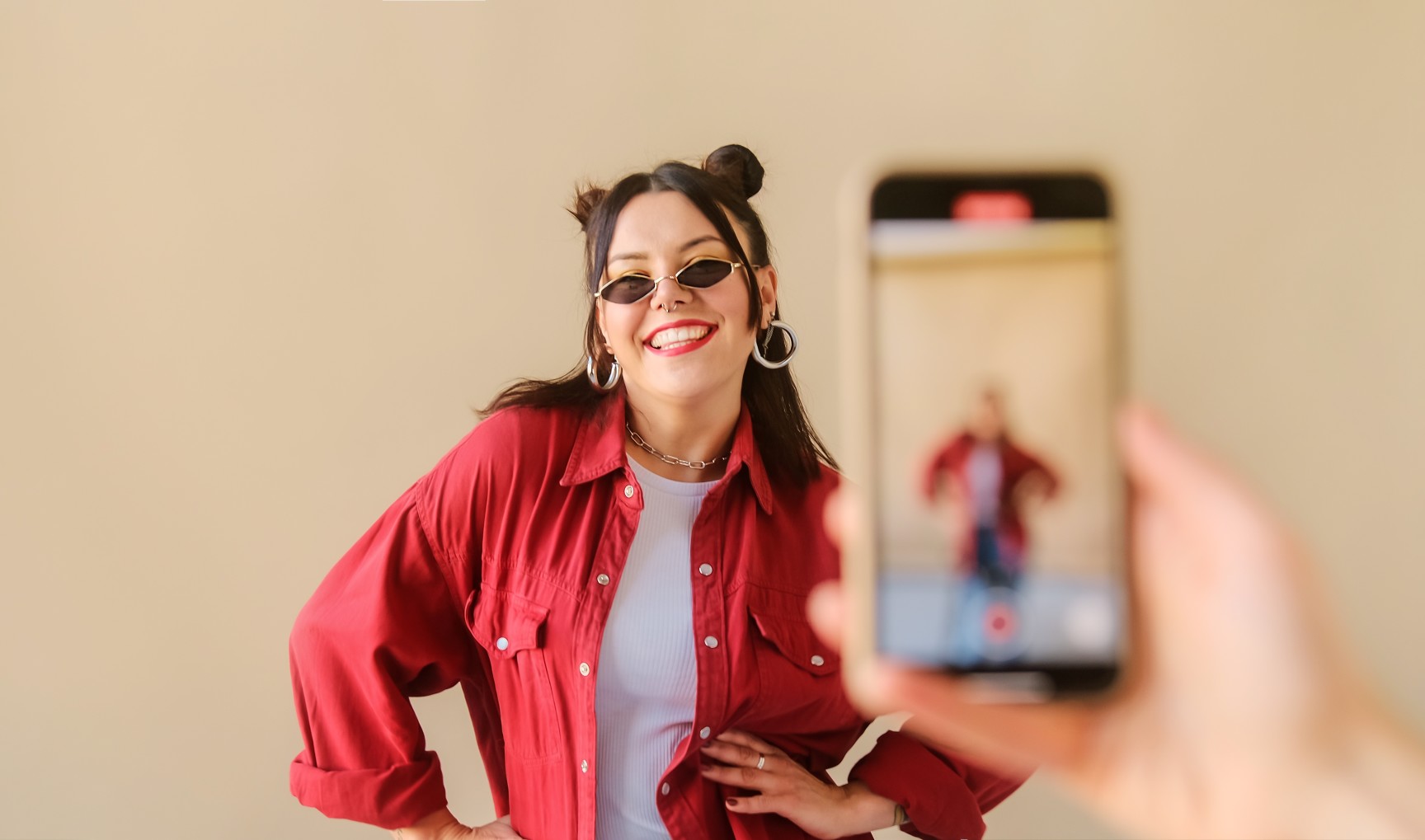 Phone recording a woman wearing a red jacket while smiling