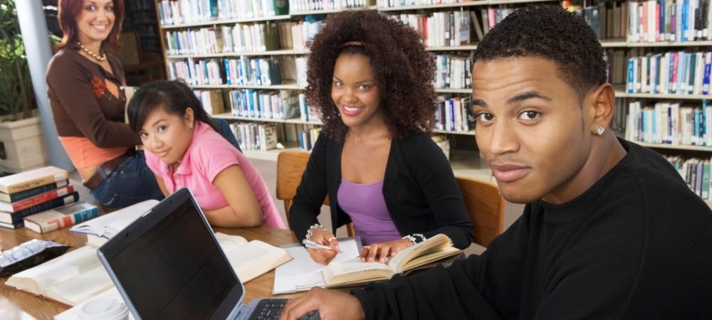 Four diverse students studying together in a library.
