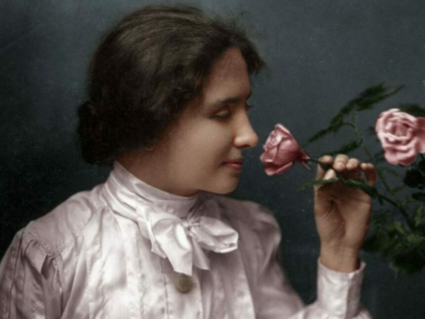 A coloured image of helen keller holding a flower from a bouquet.