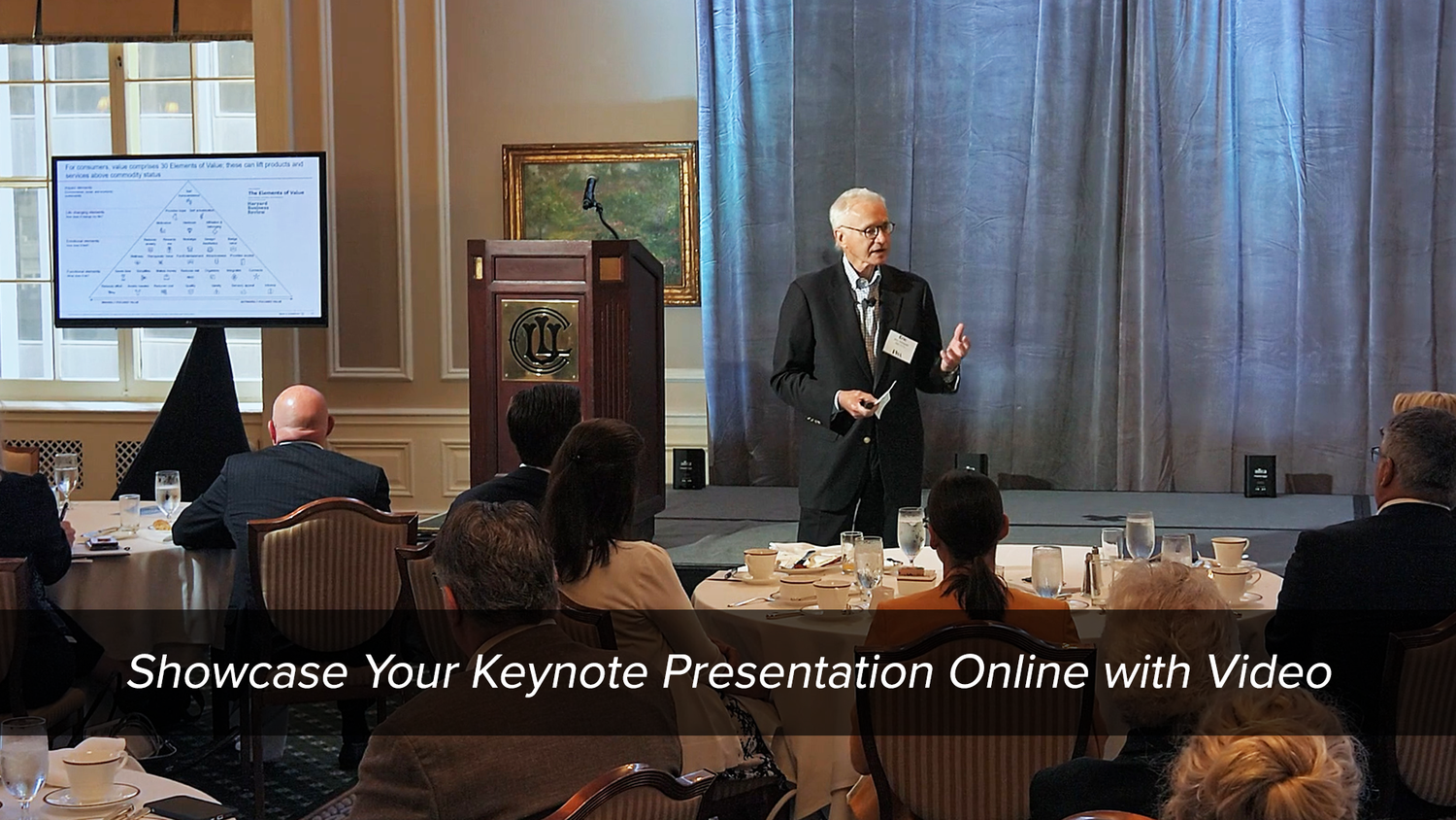 A presenter delivering a keynote speech to an attentive audience in a formal setting, with a text overlay suggesting the sharing of such presentations online through video.