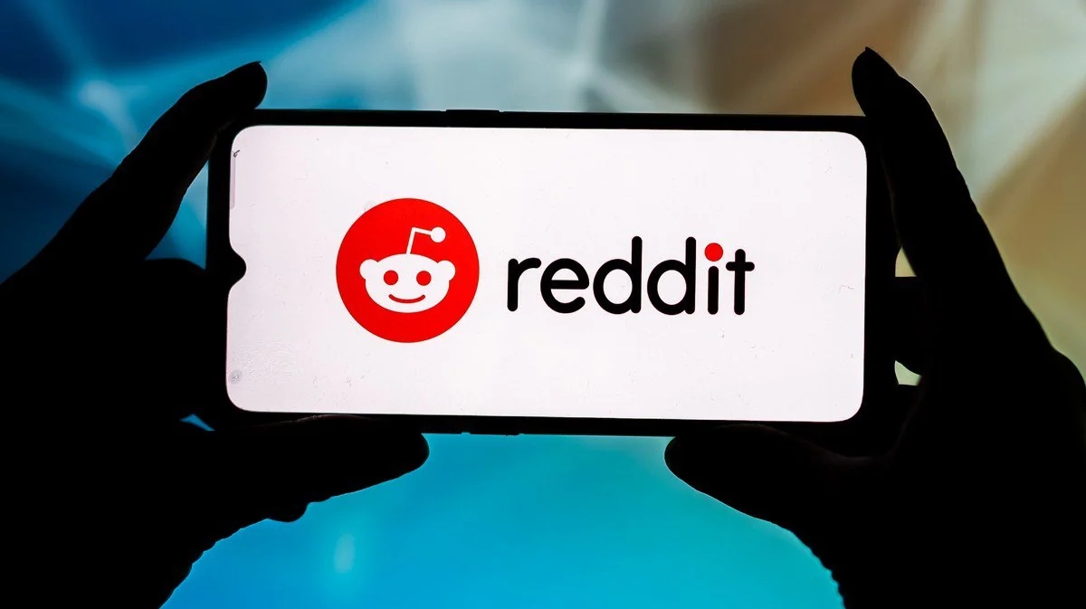 A man holding a phone with Reddit logo