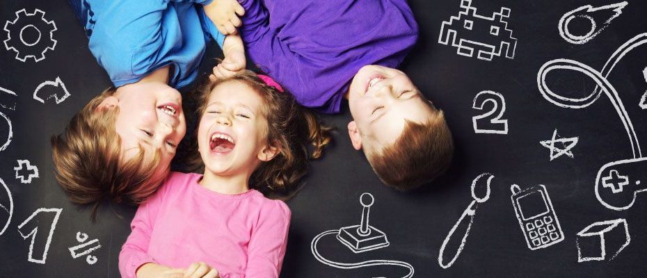 Three joyful children lying on a chalkboard surface filled with doodles of educational and playful symbols, conveying a sense of fun, creativity, and learning.