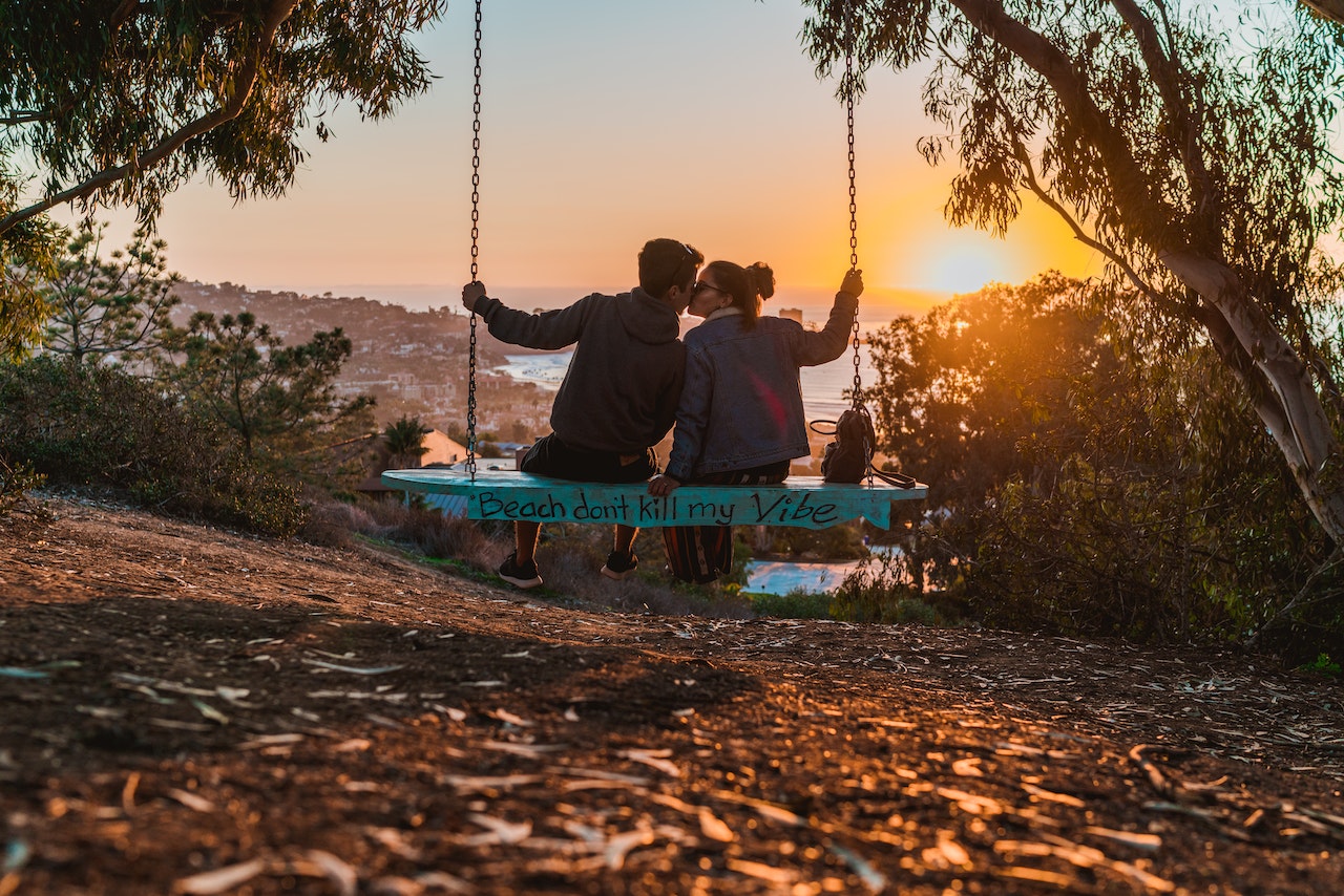 A couple kissing on a swing during sunset
