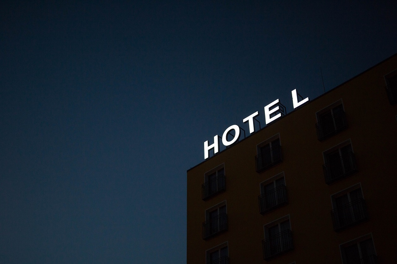 A low-angle view of a hotel lighted signage on top of brown building during nighttime