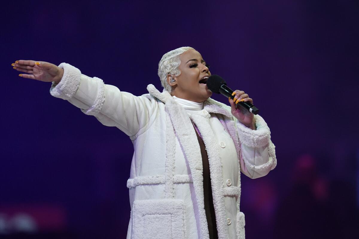 Bobbi Storm wearing a white long coat while holding a mic