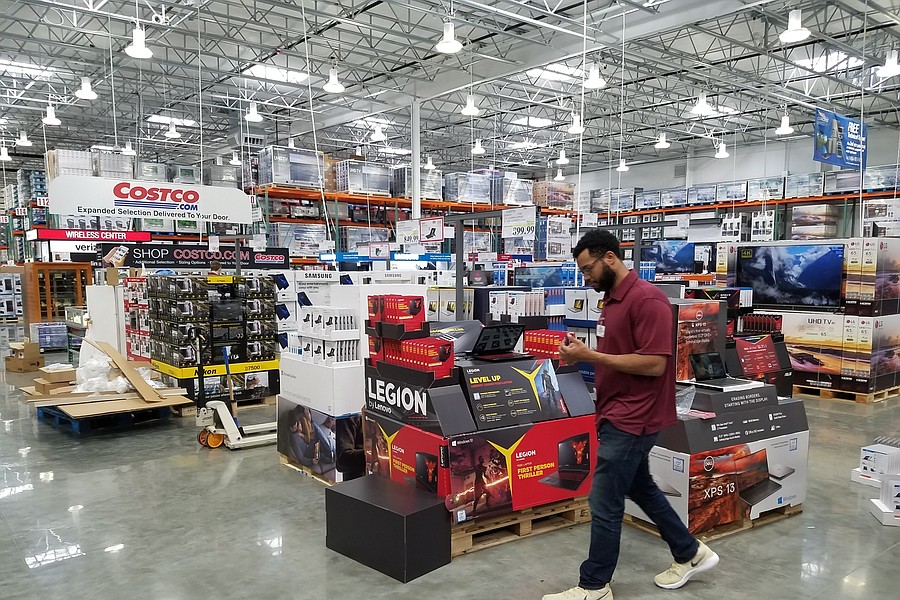 A man browsing electronic products in a spacious Costco warehouse.