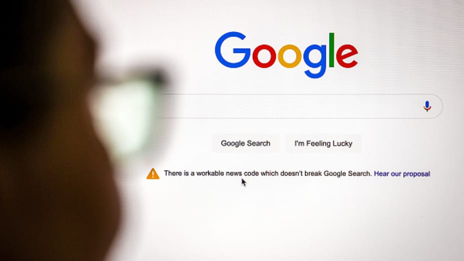 A blurred figure looking at a Google homepage which displays an alert about a "workable news code" proposal.