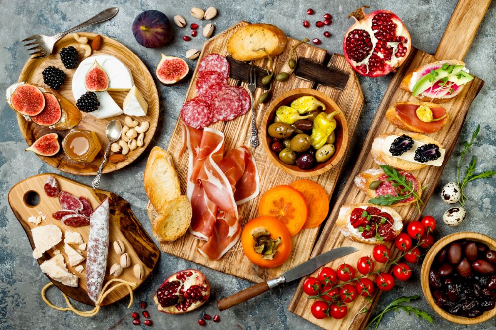 Sumptuous Mediterranean feast, featuring an assortment of cured meats, cheeses, fresh fruits, olives, and crusty bread, artfully arranged on wooden boards, creating a visually appealing and appetizing spread.