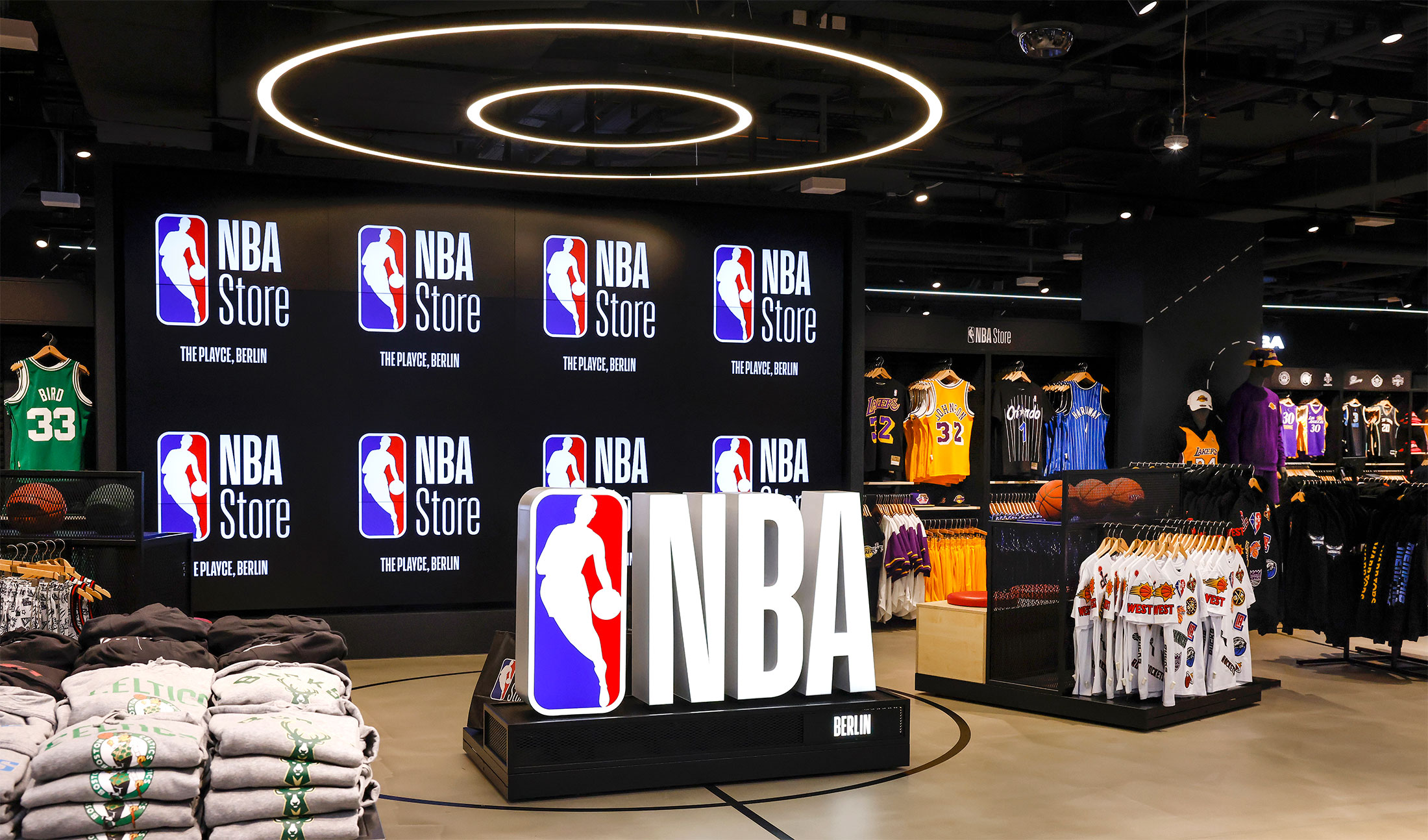 The interior of an NBA store with a prominent NBA logo in the center, surrounded by merchandise displays including jerseys, basketballs, and other NBA-themed apparel.