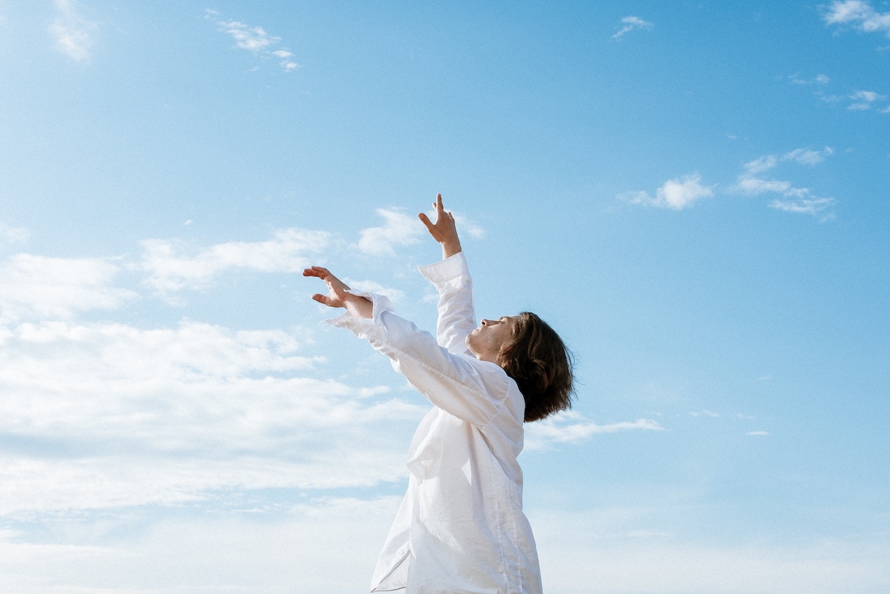 Woman in White Long Sleeve Shirt Raising Her Hands toward the blue sky