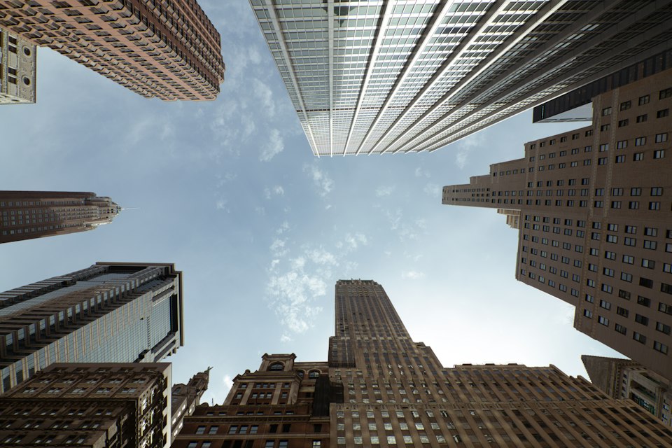 Striking upward view of a city skyline, offering a perspective framed by towering skyscrapers reaching into the vast expanse of the sky.
