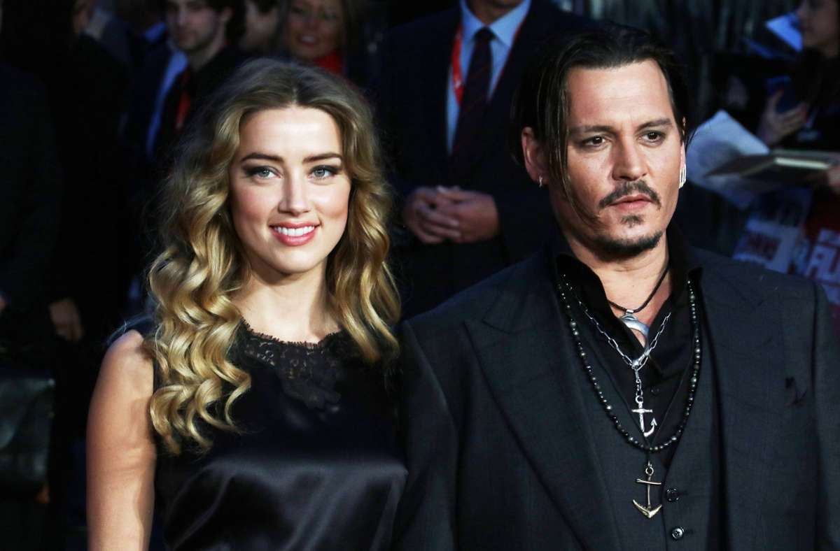 Amber Heard wearing a black dress and Johnny Depp wearing a black coat