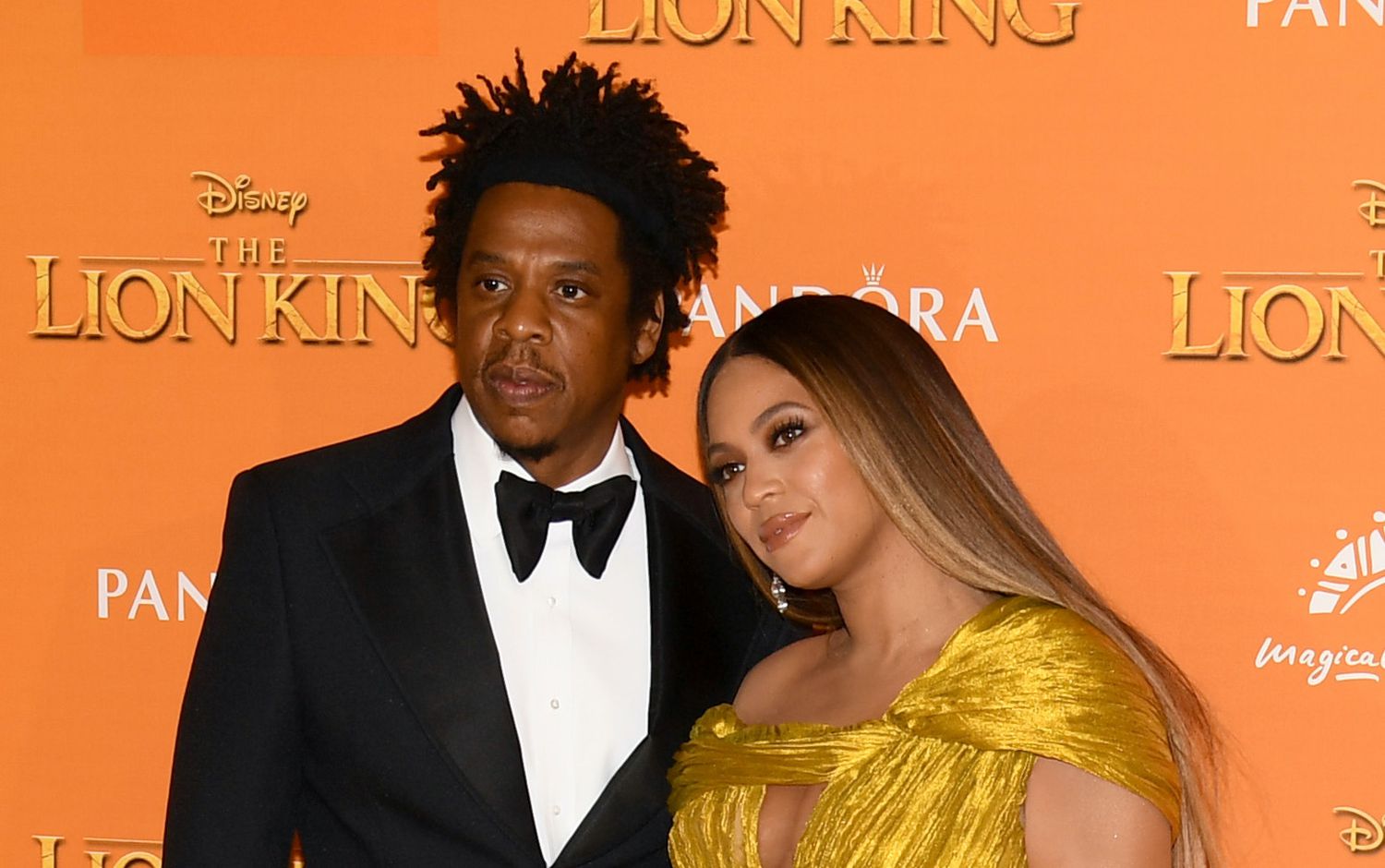 Jay-Z wearing a black suit and Beyoncé wearing a yellow dress