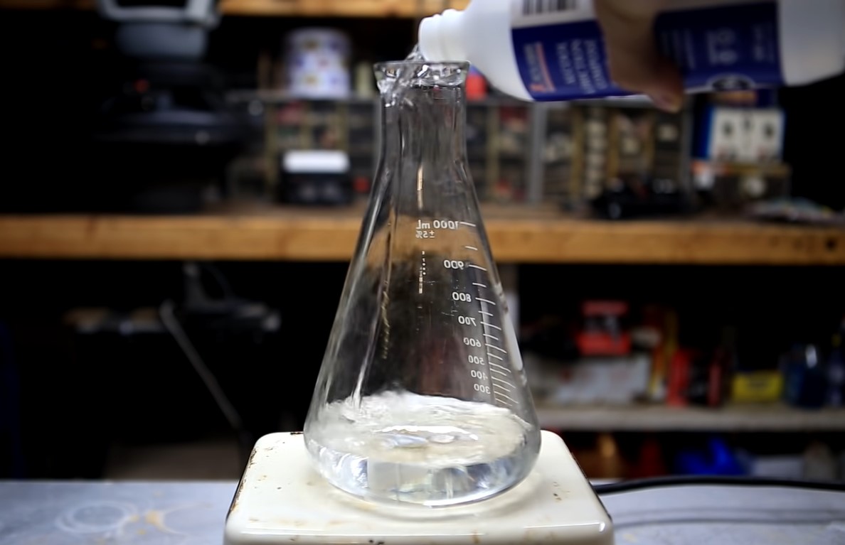 Ethanol alcohol from a white plastic container being poured into a 1,000- milliliter Erlenmeyer flask