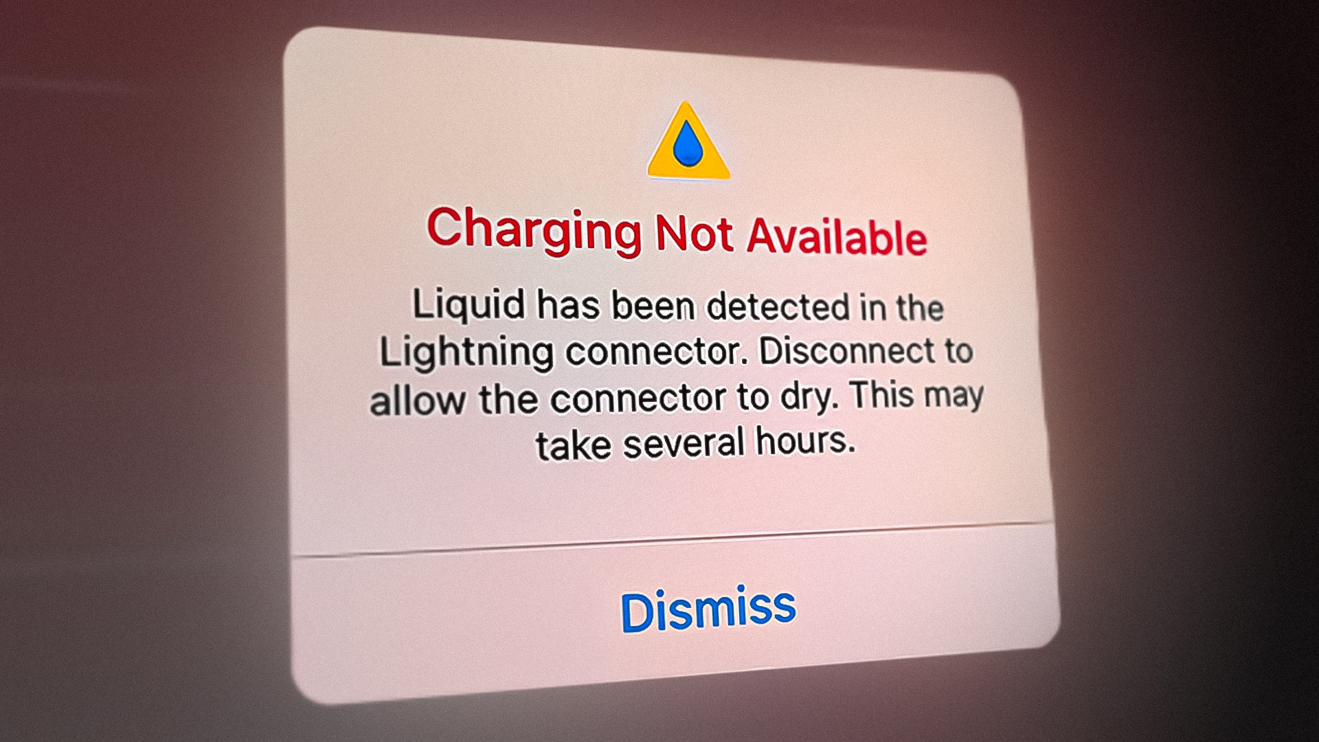 The image displays a warning message about liquid detected in the Lightning connector, preventing the device from charging.