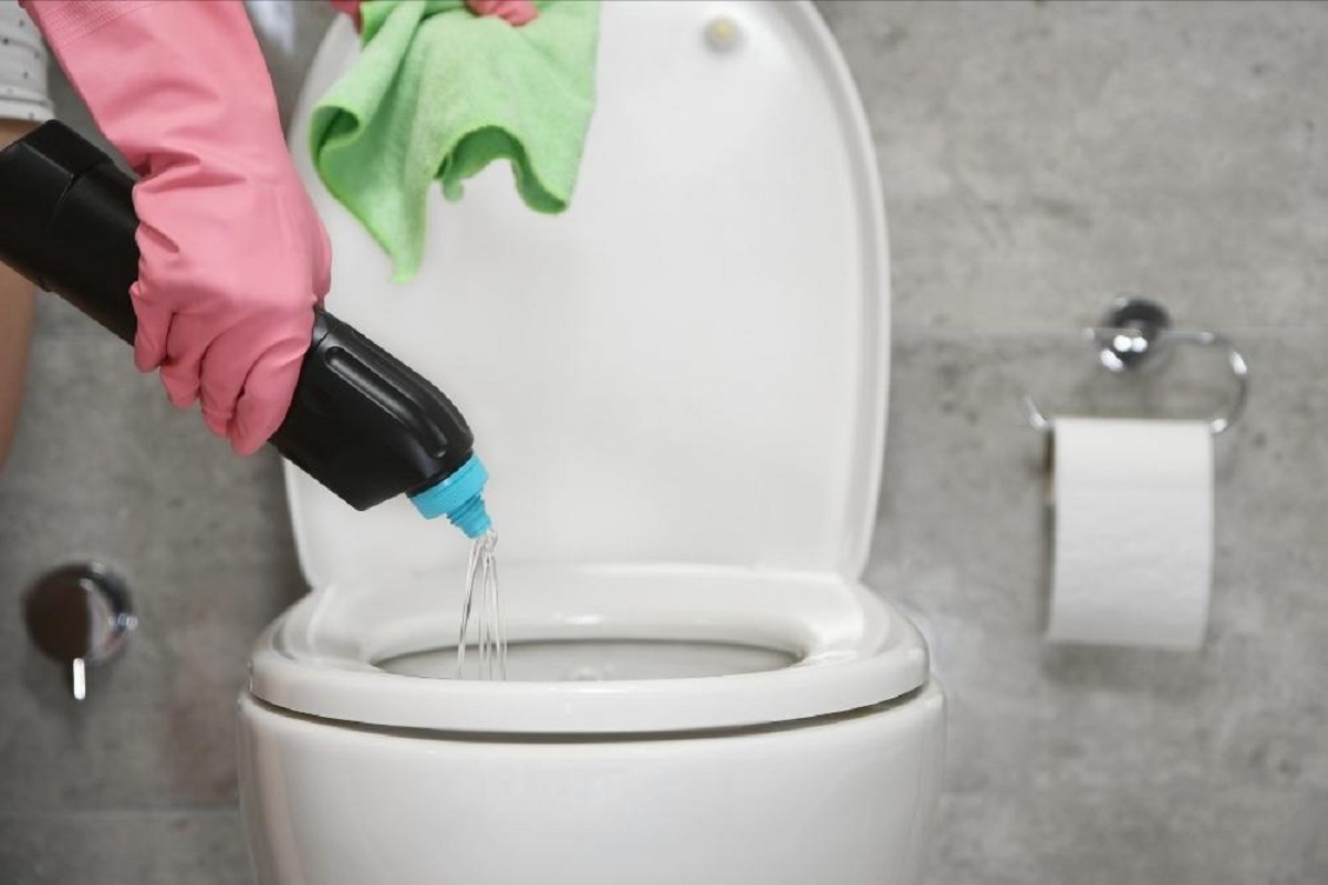 A person pouring drano into a toilet bowl.
