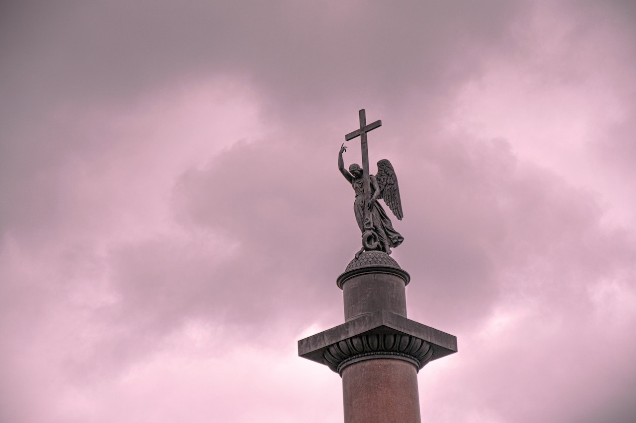 Angel with Cross Statue Against Pink Sky